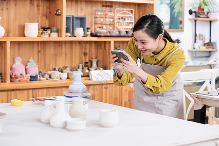 美女陶艺匠人拿手机拍陶艺品图片