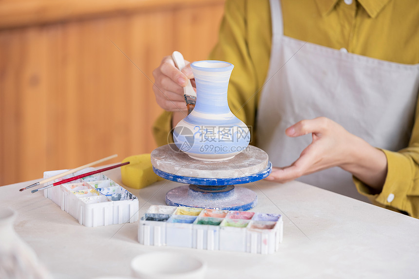 女性匠人彩绘陶艺瓶特写图片
