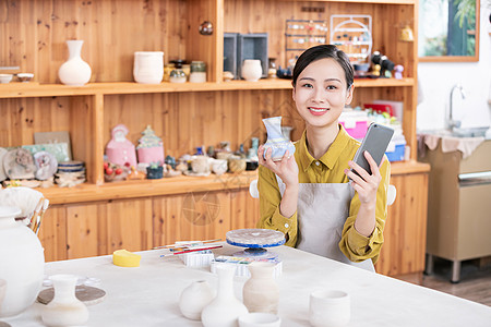 美女拿手机拍摄陶艺半成品图片