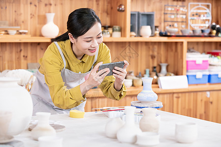 美女拿手机拍摄陶艺半成品高清图片