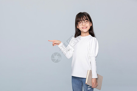 小女孩拿着练习册站着手指旁边背景图片