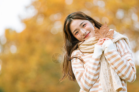 手拿树叶秋季可爱女孩手拿枫叶的背景