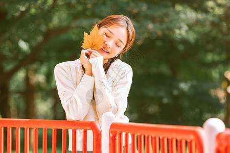 美女手持手机文艺清新美女手持落叶背景