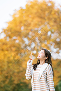 拿着树叶美女手拿树叶的秋季可爱女孩背景