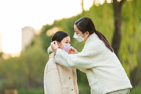 双面羊绒大衣妈妈在公园帮女儿调整口罩背景