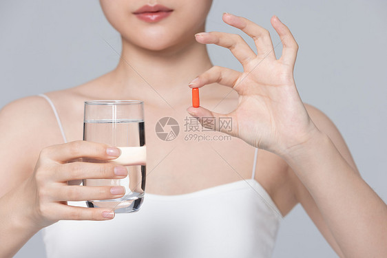 生病的女性手里拿着药和水杯图片