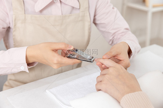 女性美甲师给顾客修剪指甲特写图片