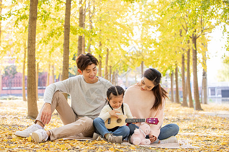 一家三口郊游父母听女儿弹尤克里里背景