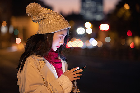 戴帽子的清纯美女冬季夜晚美女路边等候看手机背景