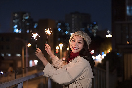 女性新年人像冬季夜晚美女天台上放烟花仙女棒背景