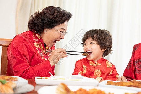 新春年夜饭奶奶夹菜喂小男孩高清图片