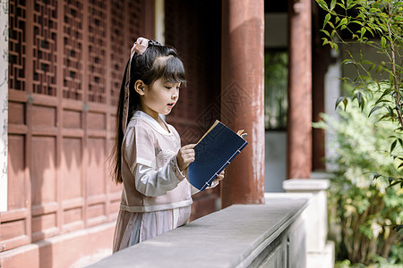 公园里的女孩汉服儿童坐在公园庭院里看书背景