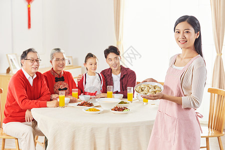 年轻妈妈春节给一家人端饺子图片