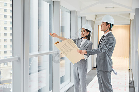 男性女性建筑工程师拿设计图纸讨论施工项目背景