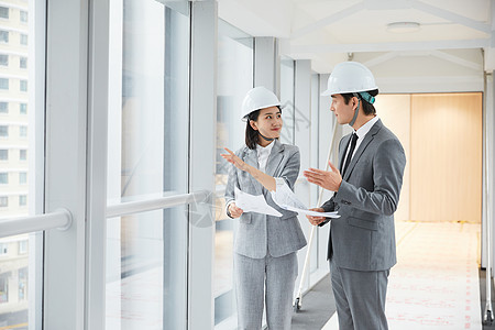 职业装男性建筑工程师拿设计图纸讨论施工项目背景