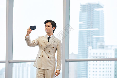 使用手机拍照的商务男士图片