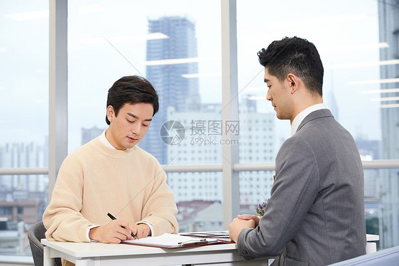 青年男性与房产销售签订合同图片