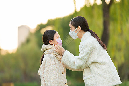 毛衣模特公园里母亲给女儿调整口罩背景