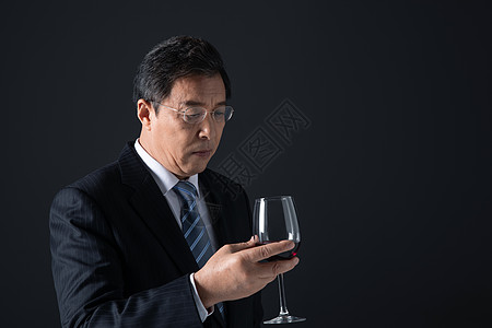 成熟男性低头看手里的酒杯高清图片