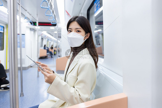女生戴口罩在地铁上使用平板电脑办公图片