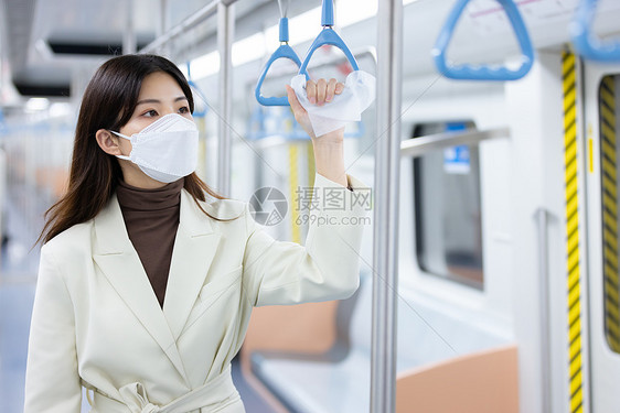 戴口罩的女性坐地铁用纸巾隔着抓扶手图片