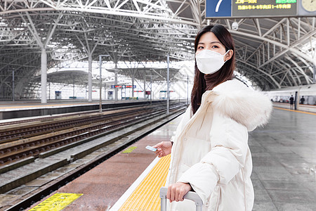 戴口罩的女性在列车站台等车拿着车票图片