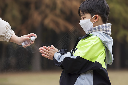 秋冬小男孩疫情期间逛公园手部消毒图片