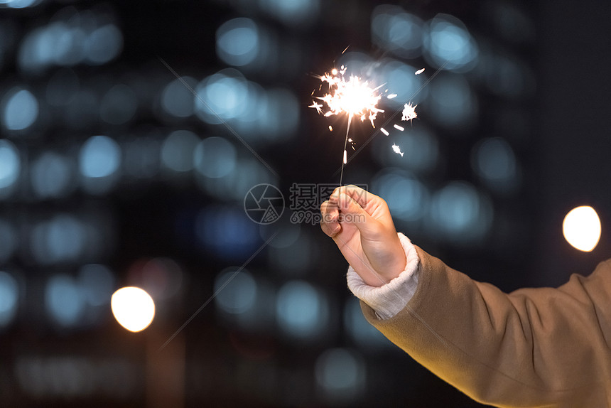 秋冬夜晚女性室外放烟花特写图片