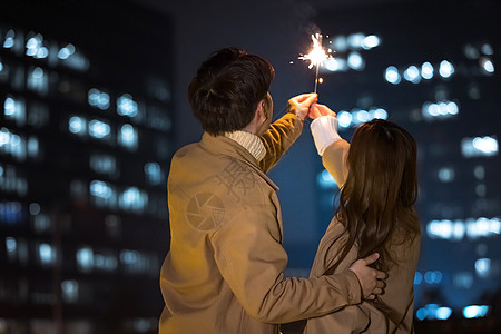 生日帽和仙女棒亲密情侣秋冬夜晚约会燃放烟花背景