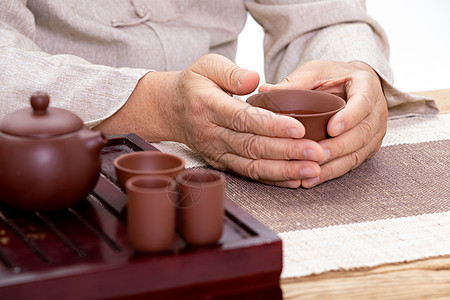 穿着唐装品茶的老人捧着茶杯特写图片