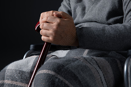 坐在轮椅上孤独的老人手握拐杖背景图片