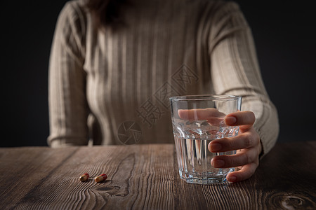 女人酒杯在黑暗中握着酒杯的女性的手背景