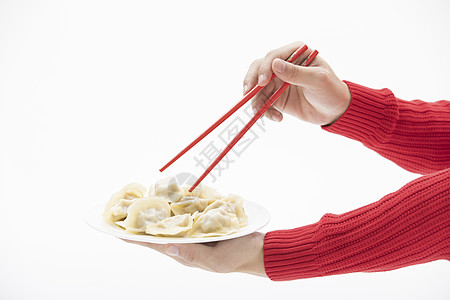 红色毛衣的手使用筷子夹饺子图片