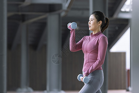 女生侧面女性在户外用哑铃健身侧面背景