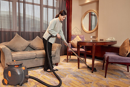 酒店服务人员使用吸尘器清洁地毯图片