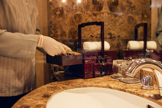 酒店保洁员整理清洁客房洗漱区域特写图片