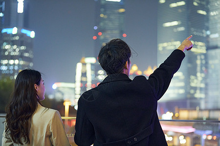 夜晚的城市年轻情侣看向夜晚城市背影背景