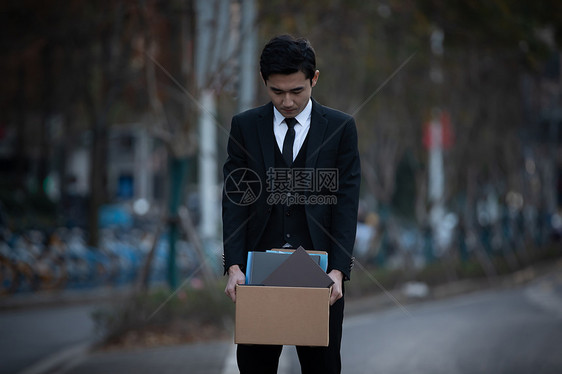 被炒鱿鱼的男性走在街头图片