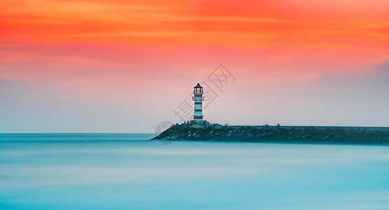 夕阳海边晚霞夕阳下的海边灯塔背景