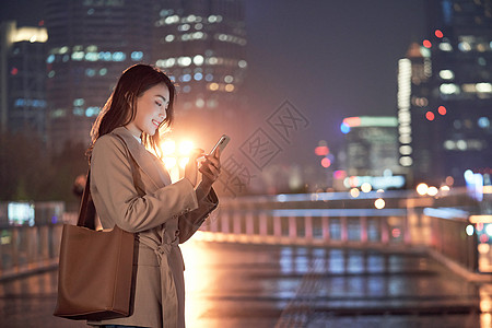 独自一个人深夜加班的都市女性使用手机打车背景