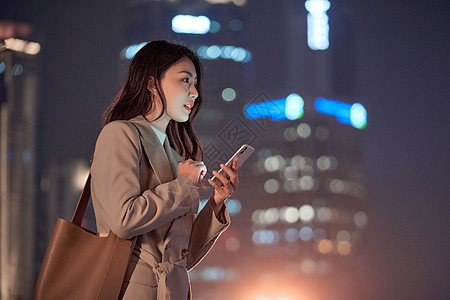 夜晚下班深夜加班的都市女性使用手机打车背景