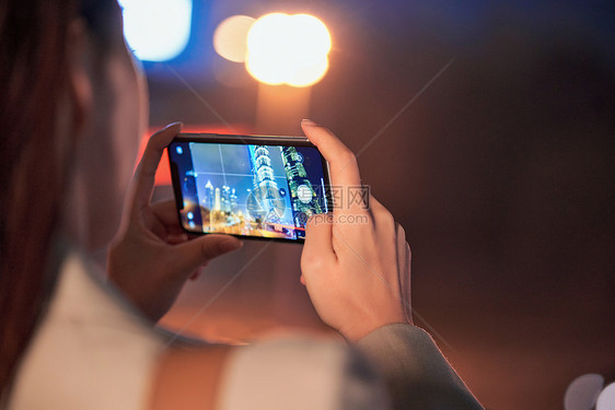 使用手机拍夜景的都市女性特写图片