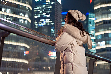 都市时尚夜晚天桥上观赏城市夜景的女性背景