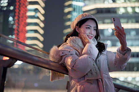 夜晚使用手机自拍的冬季女性图片