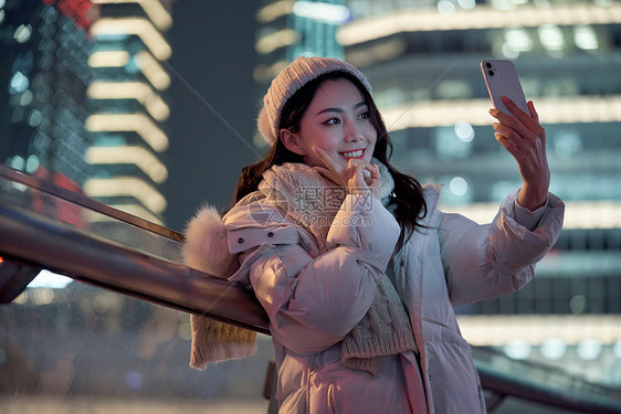 夜晚使用手机自拍的冬季女性图片