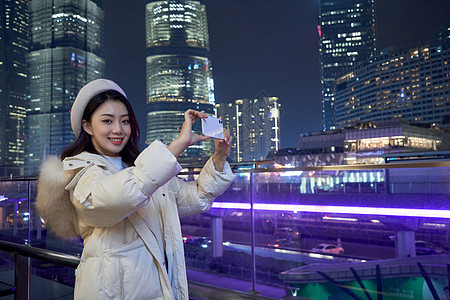 使用手机拍夜景的都市女性高清图片