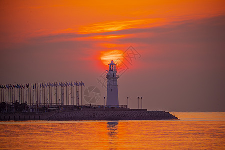 麋鹿剪影日出时红彤彤的海和伫立的灯塔背景