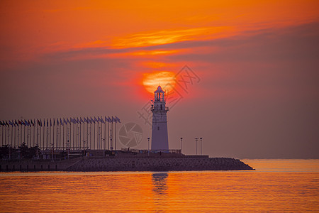 日出时红彤彤的海和伫立的灯塔图片