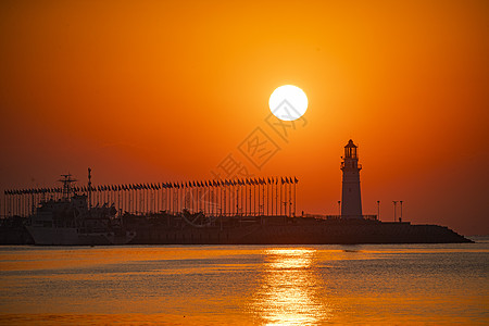 日出时红彤彤的海和伫立的灯塔高清图片