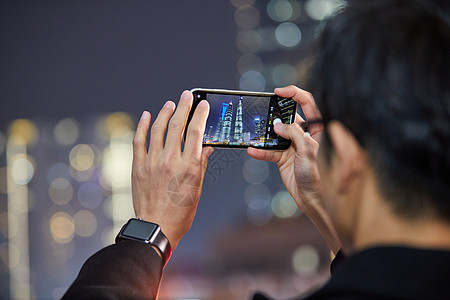 户外自拍夜晚男青年用手机拍摄城市夜景背景